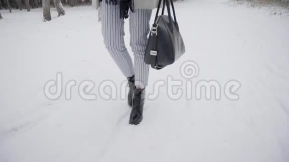 带着雨伞的漂亮年轻女人正在冬天的公园里户外散步慢动作时尚冬季肖像视频的预览图
