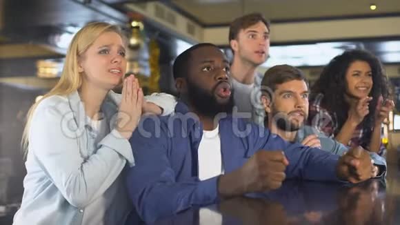 多种族的朋友在酒吧里看体育比赛为输球而沮丧视频的预览图