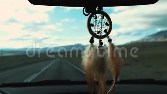 从车内后视镜中悬挂的捕梦器视图开车旅行路和雪山的景色视频的预览图