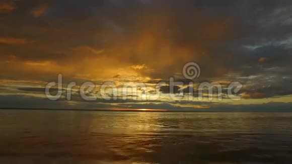 日落时大湖的景观小浪在沙岸上翻滚在地平线上可以看到红色的太阳云彩是视频的预览图
