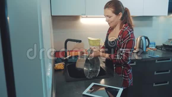 女孩在厨房砧板上洗碗女人在厨房做饭女孩在水槽里洗了一把刀视频的预览图