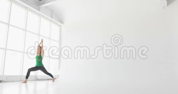 迷人的年轻女子在窗户前伸展年轻女子在工作室练习瑜伽动作和姿势视频的预览图