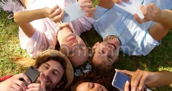 一群时髦的朋友头朝下躺着看着他们的智能手机视频的预览图
