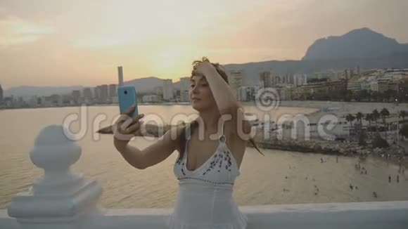 迷人的年轻女性用智能手机自拍白种人妇女用电话制作自己的肖像照片或视频视频的预览图