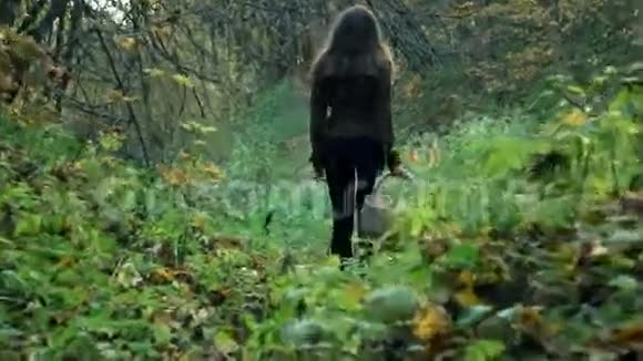 穿着棕色夹克的瘦小女人拿着篮子穿过森林4克斯泰德姆视频的预览图