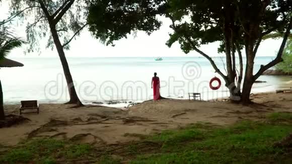 热带岛屿上的女人越南的热带穿红色裙子的女人在海洋海岸花钱女人看起来视频的预览图