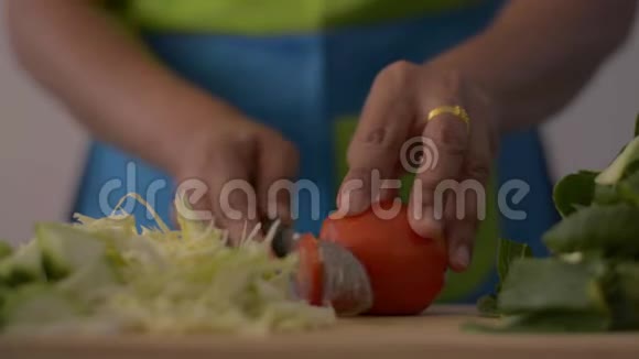 在木制砧板上切番茄的女人手的特写镜头以供桌上的健康食品视频的预览图