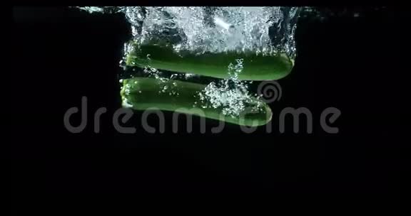 长小胡瓜或西葫芦葫芦巴皮蔬菜落入水中的黑色背景视频的预览图