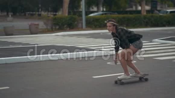 年轻漂亮的女时髦女郎白天骑滑板或长板在街上视频的预览图