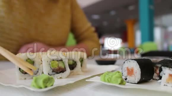 女孩坐着拿着木棍桌子上的咖啡馆里有一只绿色的芥末是寿司日本菜视频的预览图