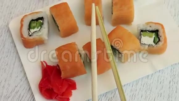 新鲜美味的寿司里面有三文鱼生姜奶酪芥末和白盘子上的木棍视频的预览图