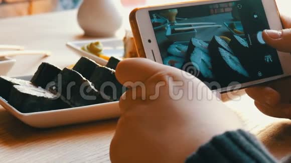 少年男孩在智能手机上拍一张食物的照片餐厅桌上的日本寿司卷视频的预览图