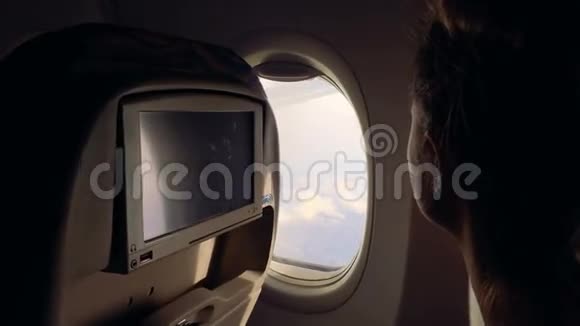 女孩坐飞机飞行欣赏舷窗的风景并关闭它视频的预览图