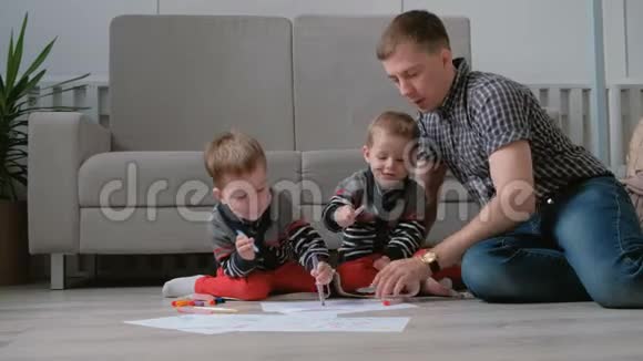 家里的爸爸和两个双胞胎兄弟一起画记号笔把毛笔放在地板上视频的预览图