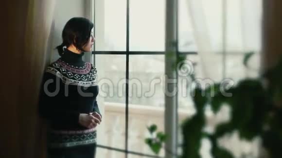 窗户旁边穿毛衣的女孩视频的预览图