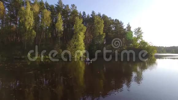 两个穿着橡皮船的渔夫在河上划桨无人机空中射击人在阳光明媚的森林里的湖上钓鱼视频的预览图