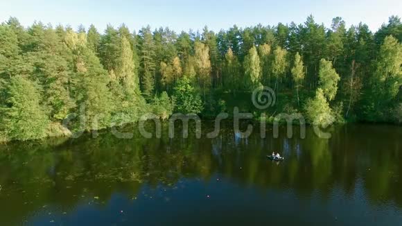 两个穿着橡皮船的渔夫在河上划桨无人机空中射击人在阳光明媚的森林里的湖上钓鱼视频的预览图