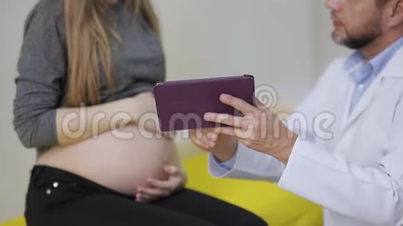 医生给孕妇看了一张药片上的超声波照片幸福的未来母亲欣赏一幅视频的预览图