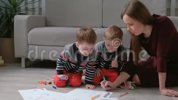 家人妈妈和两个双胞胎兄弟一起画记号摸着笔坐在地板上视频的预览图