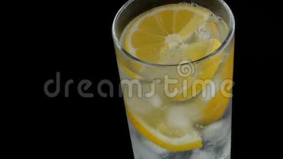 用冰块和冷苏打切好的柠檬在一个长长的杯子里黑色背景的近景新鲜柠檬酱视频的预览图