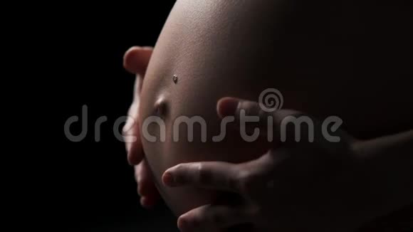 在黑暗背景下怀孕的女人关闭视频的预览图