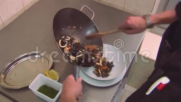 厨师用木刃从炒锅中放入准备好的贻贝虾菜餐厅厨房视频的预览图