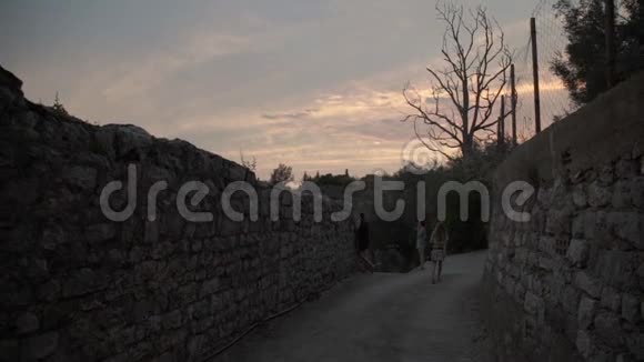 日落时男人和女人在街上散步在山里视频的预览图