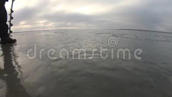 乌克兰敖德萨2017年1月黑海泰利古河口一个人钻了一个冰洞在湖上钓鱼视频的预览图