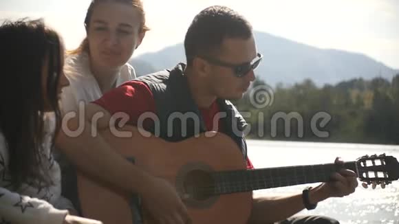 三个朋友在河岸上休息唱歌弹吉他视频的预览图