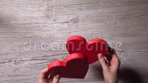 女性双手将两颗红心放在木桌上俯视约会爱情情人节观念4K视频视频的预览图
