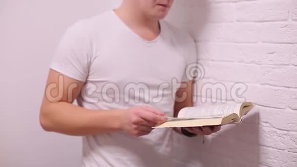 穿着白色t恤的男人翻阅一本书视频的预览图