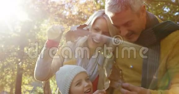 爸爸妈妈和女儿拿着树叶在户外微笑视频的预览图