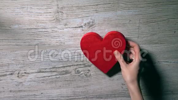 女孩把两颗红心放在一张木桌上俯视浪漫爱情情人节关系概念4K视频视频的预览图