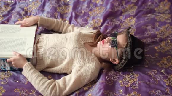 戴太阳镜戴帽子的小女孩躺在床上视频的预览图