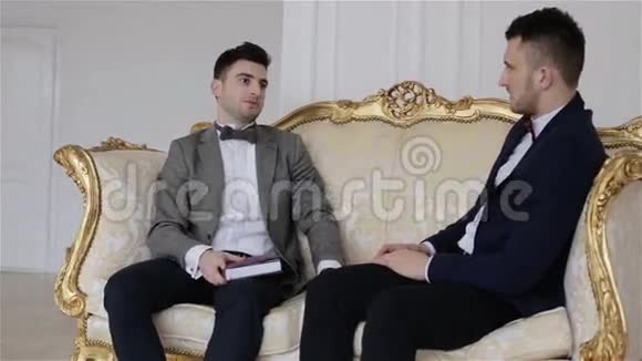 两个穿西装的英俊商人坐在沙发上讨论生意视频的预览图