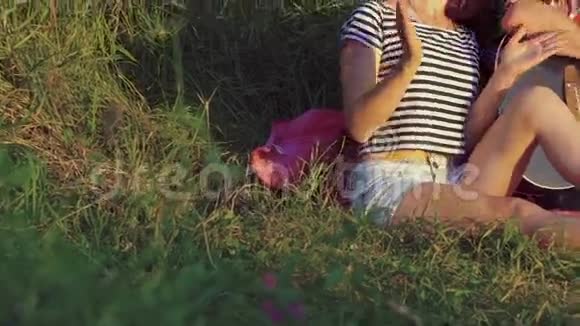 两个女孩带着有趣的男孩在阳光明媚的公园里用吉他欢呼慢动作视频的预览图