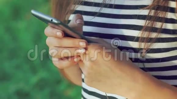 女人手拿电话在绿草背景上慢慢地视频的预览图