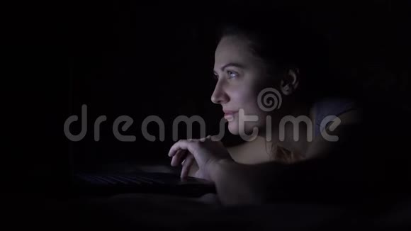 幸福的年轻女子躺在床上手提电脑不亮视频的预览图