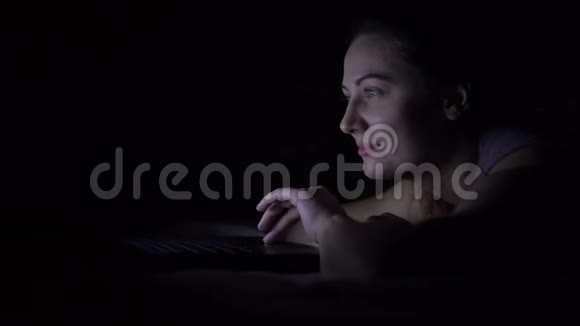快乐的年轻女子躺在床上手提电脑没有灯4公里视频的预览图