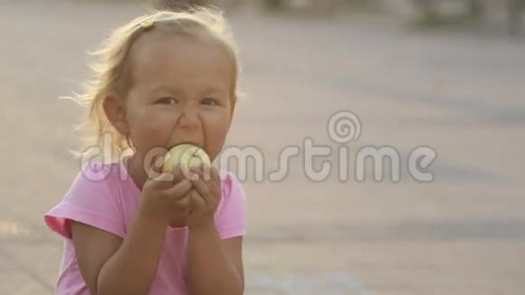 一个可爱的小女孩在公园里吃了一个新鲜的苹果伸出大手指视频的预览图