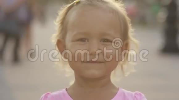 可爱的小女孩对着公共公园的摄像机眨眼视频的预览图