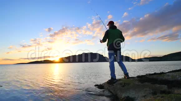 这个活跃的人正从岩石海岸在海上捕鱼渔民检查鱼线上的推饵准备好鱼竿并投掷视频的预览图