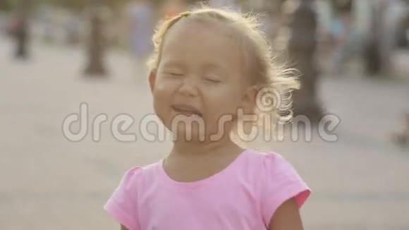 可爱的小女孩扮演猿猴眨眼在公共公园里做一个空中亲吻视频的预览图