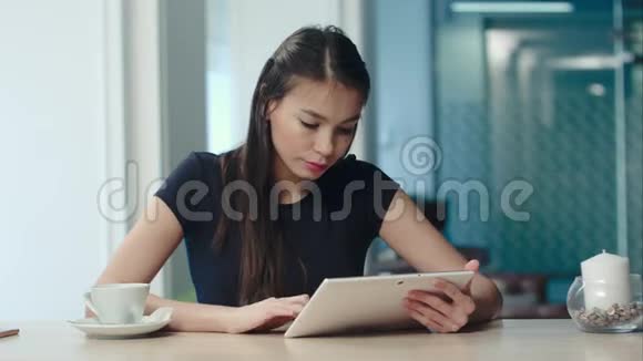 在咖啡馆喝咖啡或茶时使用数码平板电脑的年轻女性视频的预览图