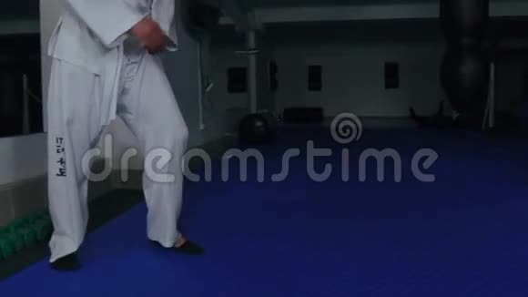 穿白色制服的人在健身房里用拳击袋训练腿慢慢地视频的预览图