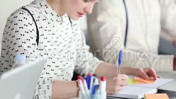 女同事在商务会议上写笔记本男同事在后台视频的预览图