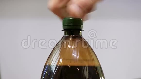 人失败打开塑料瓶的盖子里面装满了苏打水黑啤酒泡沫视频的预览图