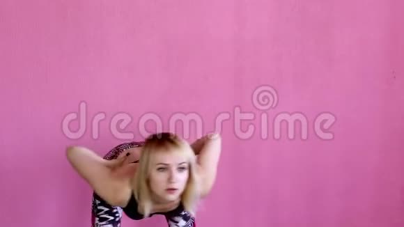 在粉色背景的健身俱乐部训练前运动型金发女孩正在热身视频的预览图