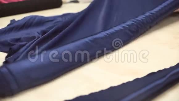 一卷深蓝色的丝绸材料展开在特殊的桌子上视频的预览图