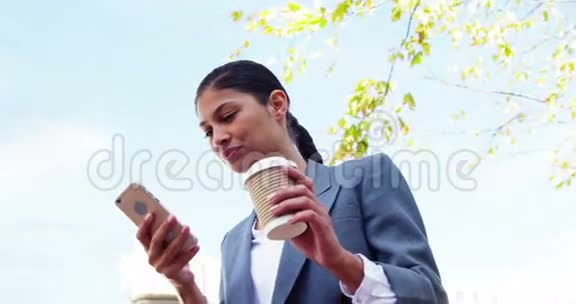 女人在外面喝咖啡用智能手机视频的预览图